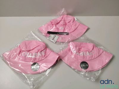 trois chapeaux roses sont emballés dans des sacs en plastique sur une table