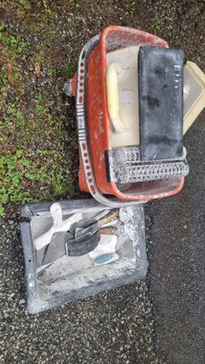 a pile of tools sitting on the ground next to a trash can