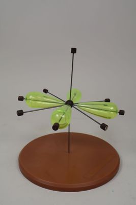un petit objet vert posé sur un socle en bois