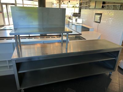 une grande table en acier inoxydable au milieu d'une cuisine