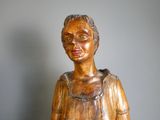 une statue en bois représentant une femme assise sur une table