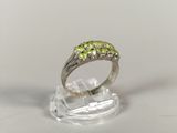sterling silver ring with peridot stones on clear acrylic base