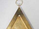 an image of a gold triangle with a ring on it