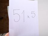 a person holding a piece of paper with the number 515 written on it