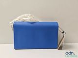 the blue purse is sitting on a white surface with a ribbon around it