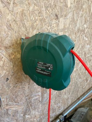 a green hose attached to a wall with a red cord
