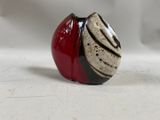 a red and black vase sitting on a white surface