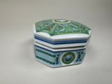 une petite boîte bleue et verte posée sur une table blanche