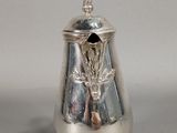 a silver vase with a bird on it on a table