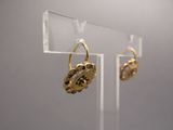 paire de boucles d'oreilles plaquées or sur un présentoir en acrylique transparent