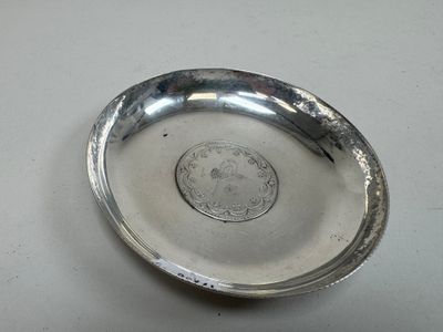 un plateau en argent posé sur une table, sur lequel se trouve une pièce de monnaie