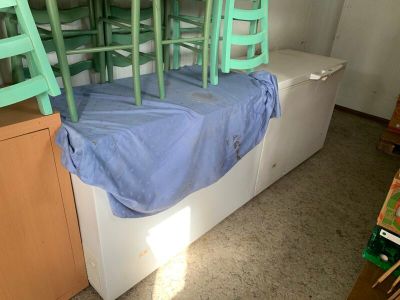 un lit recouvert d'un drap bleu, dans un coin de la pièce