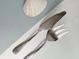 two forks and a spoon on a table with a shell