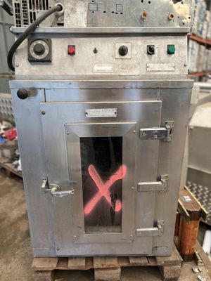 un four en métal sur lequel est dessiné un X rouge, dans un entrepôt
