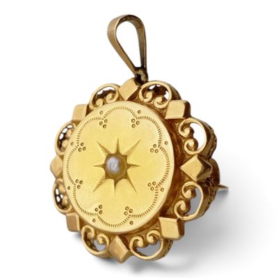 une photo d'un pendentif en forme de boussole en or, orné d'un diamant au centre