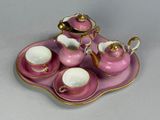 a pink tray with a tea set on top of it