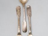 three silver spoons and two silver spoons on a table