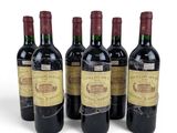 four bottles of wine are lined up on a white surface