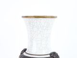a white and black vase with a gold rim on it