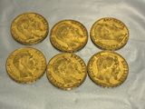 six gold sovereigns of different sizes and shapes on a blue cloth