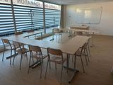 tables and chairs in a room with a large window and a whiteboard