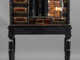 an image of a small black desk with drawers and a clock on top of it