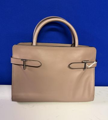a beige handbag on a white table with a blue background