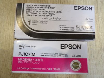 deux cartouches d'encre noires et roses posées sur une table en bois