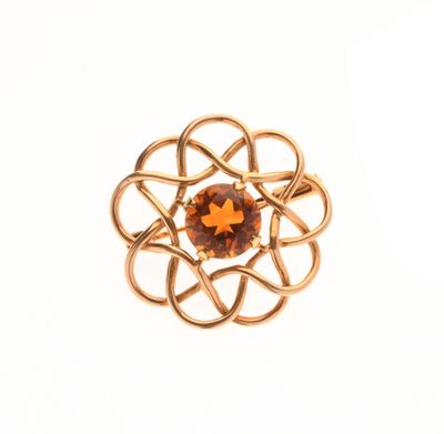 un gros plan d'une bague en or ornée d'une pierre orange au centre