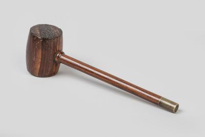 an old pipe with a wooden handle sitting on top of a white surface