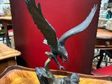 une photo représentant une statue d'aigle posée sur une table en bois