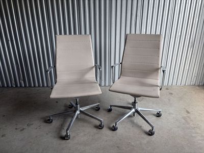 une paire de fauteuils de bureau en cuir blanc devant un mur en tôle ondulée