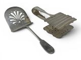 two metal utensils sitting next to each other on a white surface