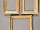 three gold picture frames hanging on a wall next to a mirror