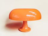 une lampe de table orange posée sur une surface blanche