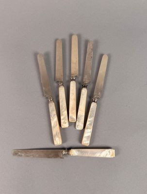 six couteaux sont alignés sur une surface grise, avec un couteau au milieu