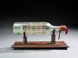 une bouteille en verre contenant un bateau, posée sur un socle en bois