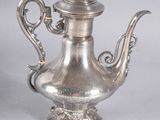 an antique silver teapot with a bird on the top of it