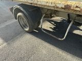 a rusted flatbed truck parked on the side of the road