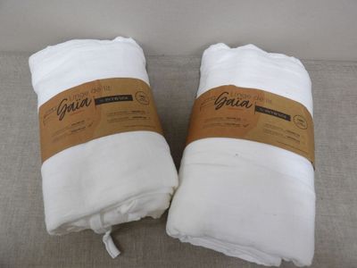 two white towels sitting on top of a couch next to each other