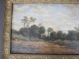 painting of a landscape with trees in a gold frame on a blue wall