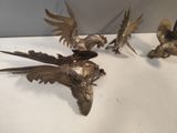 three brass birds on a white table with a white background