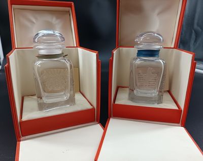 two bottles of perfume are in a red box on a table