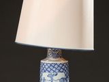 a blue and white vase with a white shade on top of it
