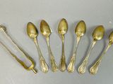 six cuillères et une fourchette sont disposées sur une table