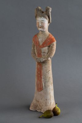 statue d'une femme tenant un bol de fruits à côté d'une banane