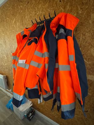 de nombreuses vestes orange accrochées à un mur dans une pièce