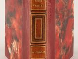 a close up of a book on a white surface with a red cover