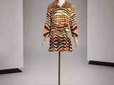 une robe orange et noire posée sur un mannequin dans une pièce