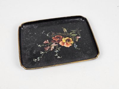 un plateau noir orné de fleurs, posé sur une surface blanche